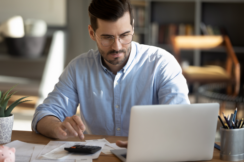 A man focused on his laptop, sitting at a desk, engrossed in work.