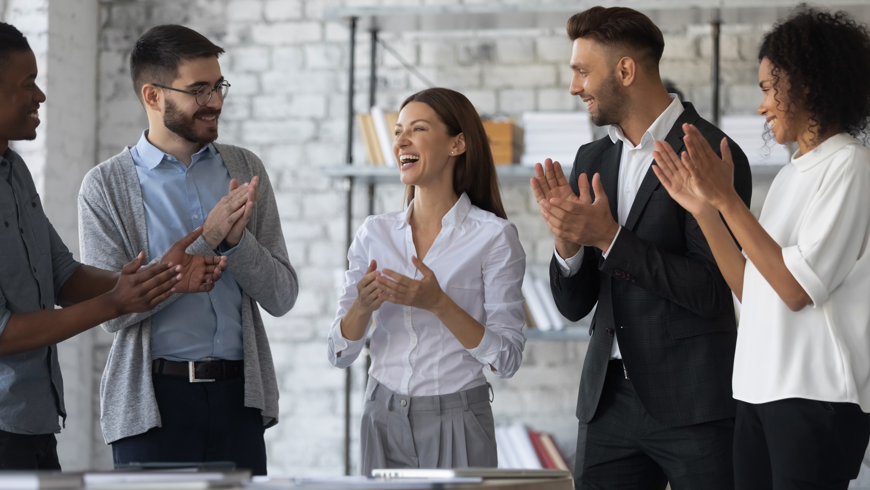 A group of business professionals applauding in unison, showing their appreciation and support for a successful achievement.